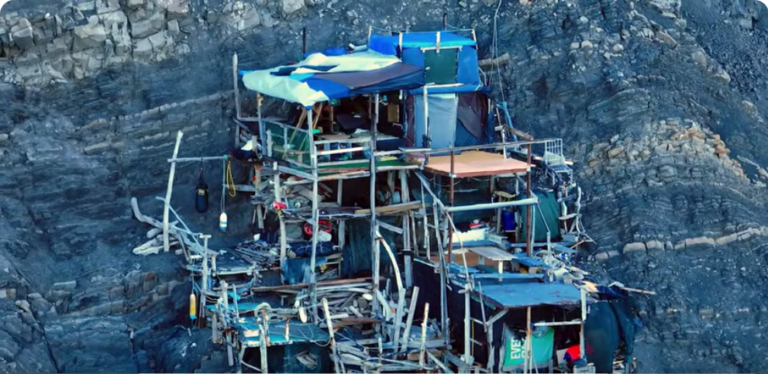 A Driftwood Shack Built On A Cliff Face Over The Ocean Natural