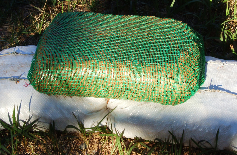 Open weave fruit/vegetable bag (Hiperadobe) on polypropylene gravel-bag foundation.