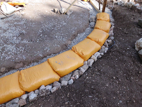 Earthbag foundation made with gravel-filled bags on a rubble trench.