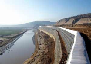 Large earthbag retaining wall reinforces the embankment between river and highway