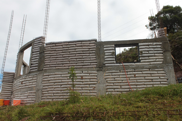 Earthbags are confined within a reinforced concrete post and beam framework.