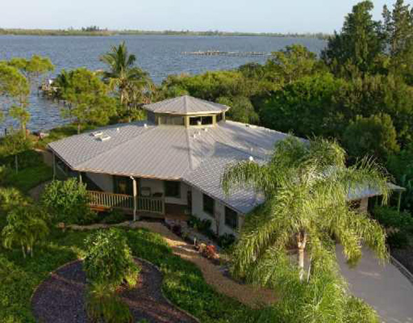 Island style home with cupola, bamboo, and wrap-around deck with water views.